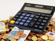 Een rekenmachine bovenop een grote hoeveelheid muntjes