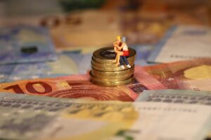 Brief- en muntgeld met bovenop een stapeltje munten twee miniatuurfiguren